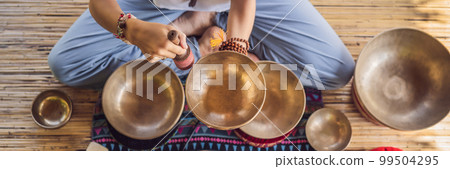 BANNER, LONG FORMAT Nepal Buddha copper singing bowl at spa salon. Young beautiful woman doing massage therapy singing bowls in the Spa against a waterfall. Sound therapy, recreation, meditation 99504295