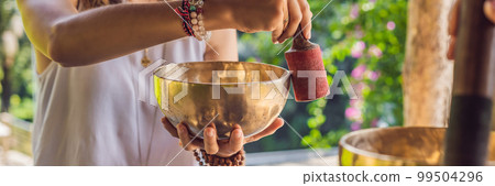 BANNER, LONG FORMAT Nepal Buddha copper singing bowl at spa salon. Young beautiful woman doing massage therapy singing bowls in the Spa against a waterfall. Sound therapy, recreation, meditation 99504296