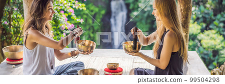 BANNER, LONG FORMAT Nepal Buddha copper singing bowl at spa salon. Young beautiful woman doing massage therapy singing bowls in the Spa against a waterfall. Sound therapy, recreation, meditation 99504298