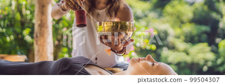 BANNER, LONG FORMAT Nepal Buddha copper singing bowl at spa salon. Young beautiful woman doing massage therapy singing bowls in the Spa against a waterfall. Sound therapy, recreation, meditation 99504307