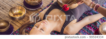 BANNER, LONG FORMAT Nepal Buddha copper singing bowl at spa salon. Young beautiful woman doing massage therapy singing bowls in the Spa against a waterfall. Sound therapy, recreation, meditation BANNER, LONG FORMAT Nepal Buddha copper singing bowl at spa salon. Young beautiful woman doing massage therapy singing bowls in the Spa against a waterfall. Sound therapy, recreation, meditation 99504334