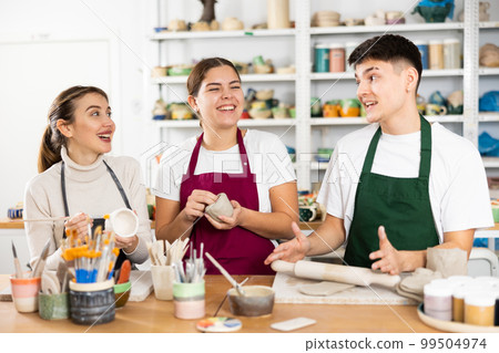 Two young women and young man making pottery Two young women and young man making pottery 99504974