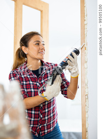 Cheerful woman using spray foam Cheerful woman using spray foam 99505100