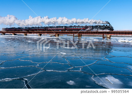 The steam locomotive Fuyu no Shitsugen runs on the Kushiro River iron bridge with lotus leaves while emitting white smoke. The steam locomotive Fuyu no Shitsugen runs on the Kushiro River iron bridge with lotus leaves while emitting white smoke. 99505564