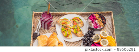 BANNER, LONG FORMAT Breakfast tray in swimming pool, floating breakfast in luxury hotel smoothies and fruit plate, smoothie bowl by the hotel pool. Exotic summer diet. Tropical beach lifestyle. Bali BANNER, LONG FORMAT Breakfast tray in swimming pool, floating breakfast in luxury hotel smoothies and fruit plate, smoothie bowl by the hotel pool. Exotic summer diet. Tropical beach lifestyle. Bali 99506291