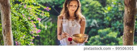 Woman playing on Tibetan singing bowl while sitting on yoga mat against a waterfall. Vintage tonned. Beautiful girl with mala beads meditating BANNER, LONG FORMAT Woman playing on Tibetan singing bowl while sitting on yoga mat against a waterfall. Vintage tonned. Beautiful girl with mala beads meditating BANNER, LONG FORMAT 99506301