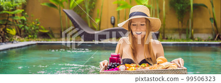 BANNER, LONG FORMAT Breakfast tray in swimming pool, floating breakfast in luxury hotel. Girl relaxing in the pool drinking smoothies and eating fruit plate, smoothie bowl by the hotel pool. Exotic 99506323
