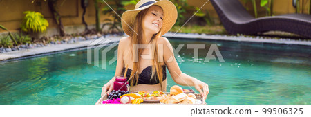 BANNER, LONG FORMAT Breakfast tray in swimming pool, floating breakfast in luxury hotel. Girl relaxing in the pool drinking smoothies and eating fruit plate, smoothie bowl by the hotel pool. Exotic BANNER, LONG FORMAT Breakfast tray in swimming pool, floating breakfast in luxury hotel. Girl relaxing in the pool drinking smoothies and eating fruit plate, smoothie bowl by the hotel pool. Exotic 99506325