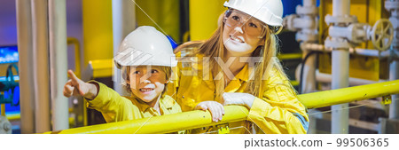 Young woman and a little boy are both in a yellow work uniform, glasses, and helmet in an industrial environment, oil Platform or liquefied gas plant BANNER, LONG FORMAT 99506365