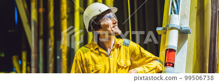 Young man in a yellow work uniform, glasses and helmet in industrial environment,oil Platform or liquefied gas plant BANNER, LONG FORMAT Young man in a yellow work uniform, glasses and helmet in industrial environment,oil Platform or liquefied gas plant BANNER, LONG FORMAT 99506738