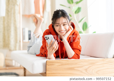 年輕女子在客廳看智慧型手機 99507152