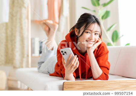 年輕女子在客廳看智慧型手機 年輕女子在客廳看智慧型手機 99507154