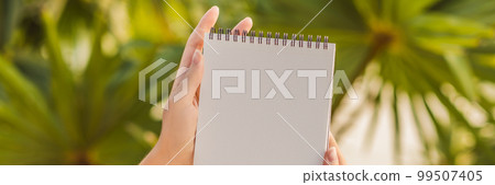 Women's hands in a tropical background holding a signboard, drawing block, paper, mockup BANNER, LONG FORMAT Women's hands in a tropical background holding a signboard, drawing block, paper, mockup BANNER, LONG FORMAT 99507405