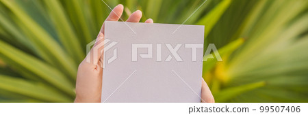 Women's hands in a tropical background holding a signboard paper, mockup BANNER, LONG FORMAT 99507406