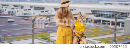 BANNER, LONG FORMAT Family at airport before flight. Mother and son waiting to board at departure gate of modern international terminal. Traveling and flying with children. Mom with kid boarding 99507453