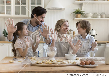 Joyful parents and two happy kids in aprons baking together 99507617