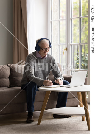 Cheerful older retired man wearing wireless headphones 99507702
