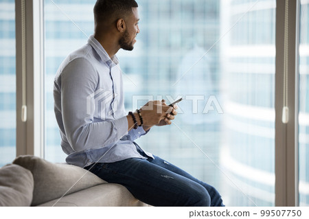 Dreamy handsome young African business man holding mobile phone 99507750