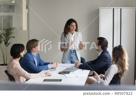 Serious pretty project leader woman talking to employees on meeting Serious pretty project leader woman talking to employees on meeting 99507822