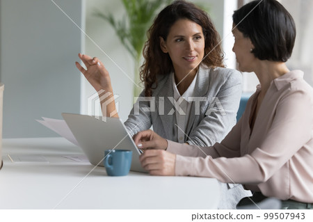 Busy engaged different aged office coworkers talking at laptop Busy engaged different aged office coworkers talking at laptop 99507943