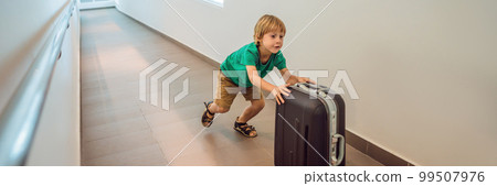 Funny little boy going on vacations trip with suitcase at airport, indoors BANNER, LONG FORMAT 99507976