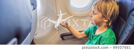 Little boy play with toy plane in the commercial jet airplane flying on vacation BANNER, LONG FORMAT 99507981