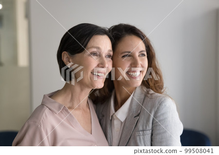 Happy beautiful senior mom and successful adult daughter standing close 99508041