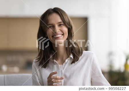 Home portrait of happy beautiful young woman holding transparent glass Home portrait of happy beautiful young woman holding transparent glass 99508227