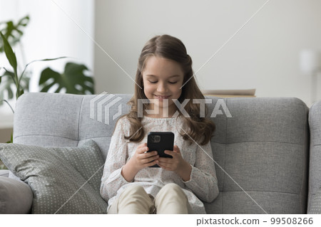 Cheerful little kid girl playing video game on mobile phone 99508266
