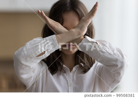 Serious young woman showing crossed arms at camera Serious young woman showing crossed arms at camera 99508381