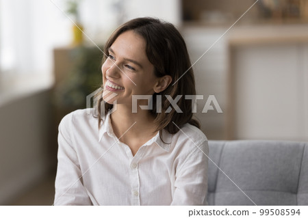 Cheerful beautiful young woman sitting on couch at home 99508594
