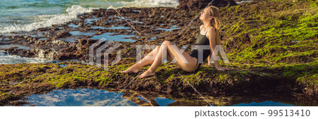 Young woman tourist on Pantai Tegal Wangi Beach sitting in a bath of sea water, Bali Island, Indonesia. Bali Travel Concept BANNER, LONG FORMAT 99513410