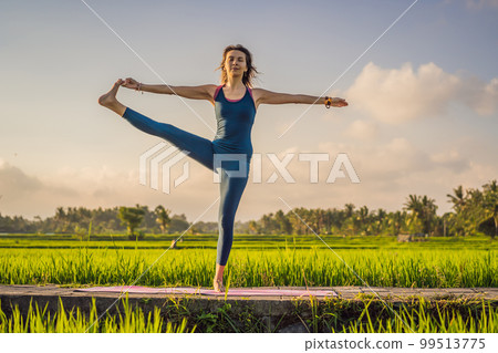 Young woman practice yoga outdoor in rice fields in the morning during wellness retreat in Bali Young woman practice yoga outdoor in rice fields in the morning during wellness retreat in Bali 99513775