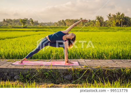 Young woman practice yoga outdoor in rice fields in the morning during wellness retreat in Bali Young woman practice yoga outdoor in rice fields in the morning during wellness retreat in Bali 99513776