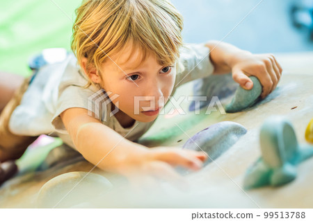 little boy climbing a rock wall in special boots. indoor 99513788