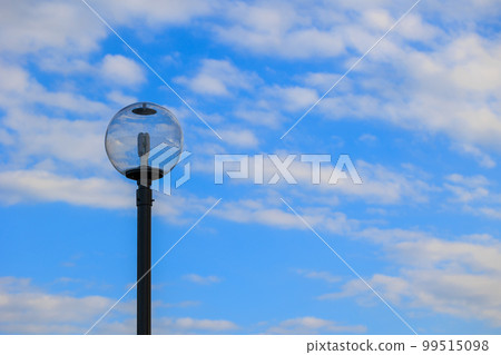 The blue sky and white clouds are reflected in the glass of the streetlight The blue sky and white clouds are reflected in the glass of the streetlight 99515098