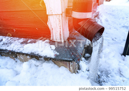 frozen water in downspout gutter of the roof drainage system with ice 99515752