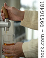 Female hand pouring beer from beer server 99516481