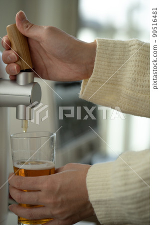 Female hand pouring beer from beer server 99516481