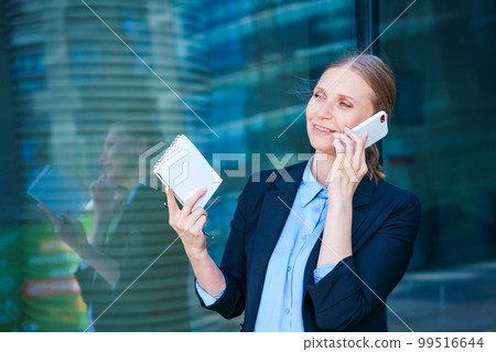 Smart professional caucasian business woman uses mobile phone in city outdoors Smart professional caucasian business woman uses mobile phone in city outdoors 99516644