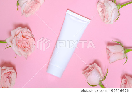 White empty cosmetic tube, on a pink background with delicate pink roses. White empty cosmetic tube, on a pink background with delicate pink roses. 99516676