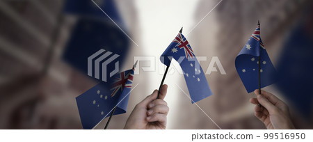 A group of people holding small flags of the Australia in their hands A group of people holding small flags of the Australia in their hands 99516950