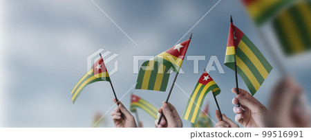 A group of people holding small flags of the Togo in their hands 99516991