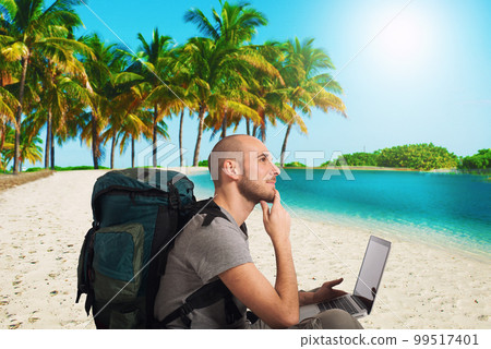 Explorer plans a new travel to a tropical beach with his laptop 99517401
