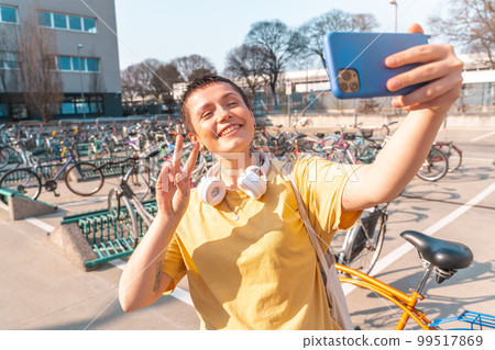 Woman takes a selfie with cellphone in a bicycle parking Woman takes a selfie with cellphone in a bicycle parking 99517869