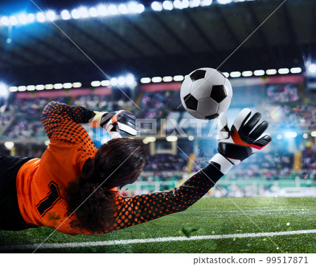 Goalkeeper catches the ball in the stadium during a football game. Goalkeeper catches the ball in the stadium during a football game. 99517871