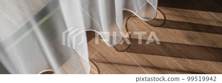 Closeup of light white curtains and brown wood laminate by window 99519942