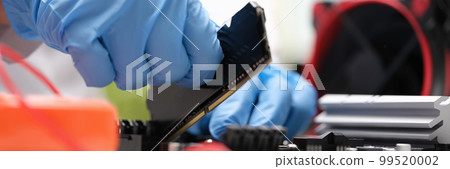 Repair engineer holds RAM chip with hands and inserts RAM of computer into socket of computer motherboard Repair engineer holds RAM chip with hands and inserts RAM of computer into socket of computer motherboard 99520002