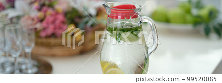 Infused detox water with cucumber, lemon and mint in jug on table 99520085