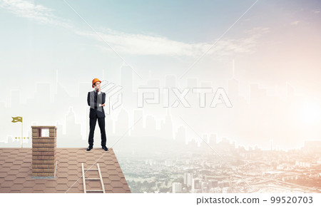 Engineer man standing on roof and looking away. Mixed media 99520703